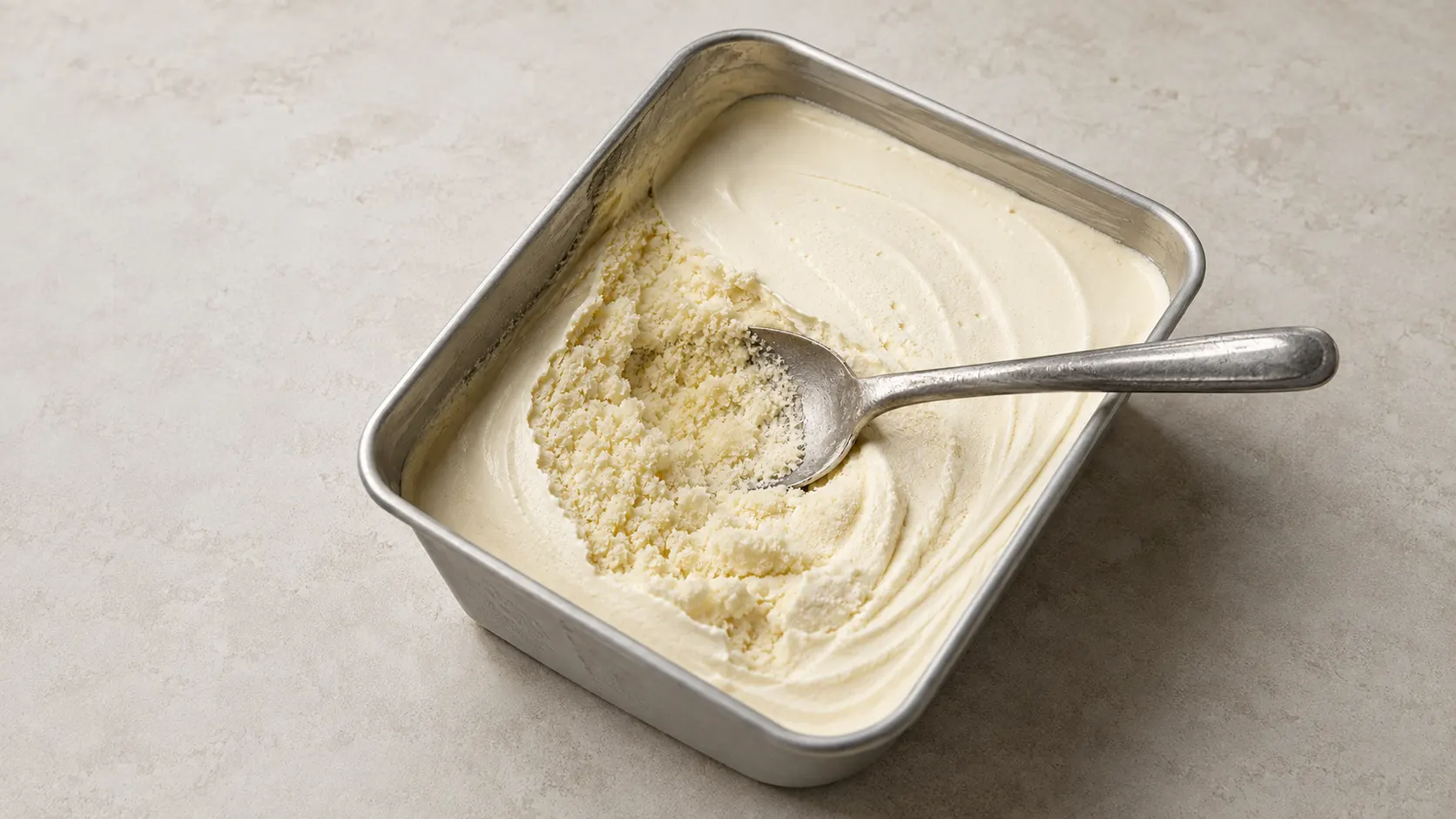 Hausgemachtes Eis mit Eiskristallen und sandiger Textur in der Wanne